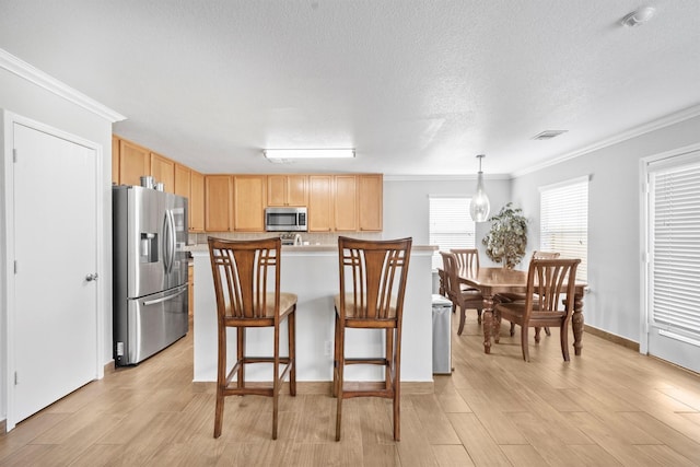 kitchen featuring light brown cabinets, appliances with stainless steel finishes, light countertops, and crown molding