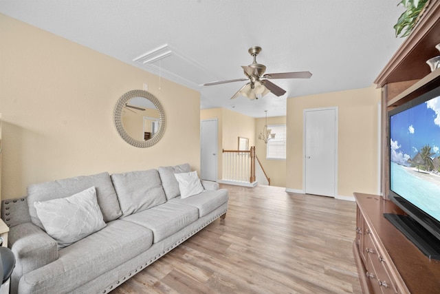 living area featuring ceiling fan, light wood-type flooring, attic access, and baseboards