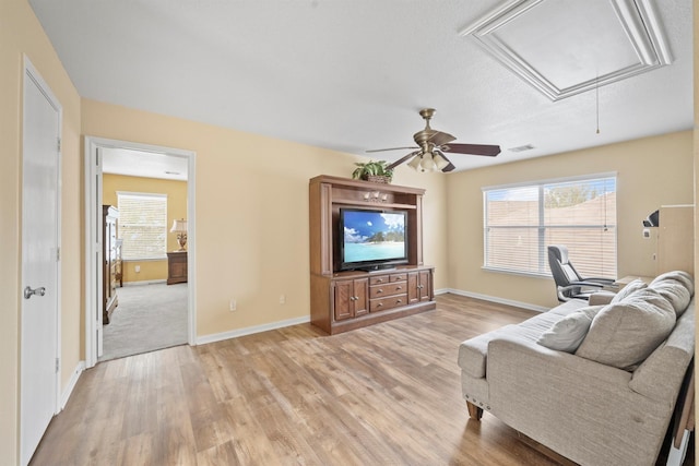 living area featuring attic access, visible vents, light wood-style floors, and baseboards