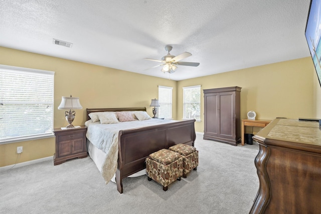 bedroom featuring visible vents, light carpet, baseboards, and a textured ceiling