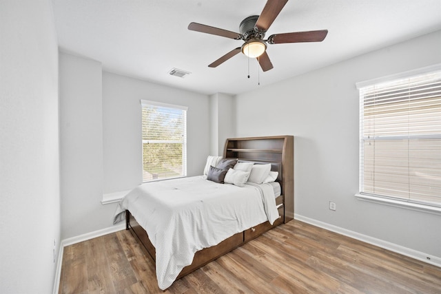 bedroom with visible vents, ceiling fan, baseboards, and wood finished floors