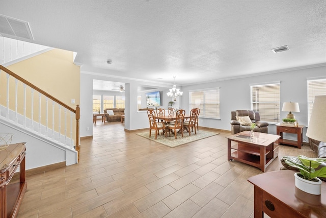 living room with visible vents, a notable chandelier, a textured ceiling, and stairs