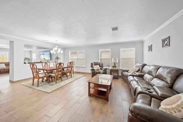 living room featuring ornamental molding, light wood-type flooring, visible vents, and a notable chandelier