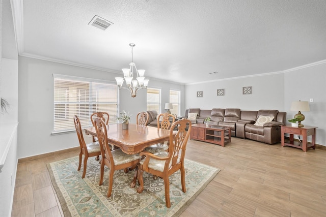 dining room featuring a chandelier, light wood-type flooring, visible vents, and a textured ceiling