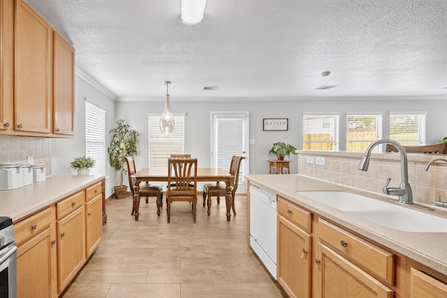 kitchen with visible vents, ornamental molding, white dishwasher, light countertops, and a sink