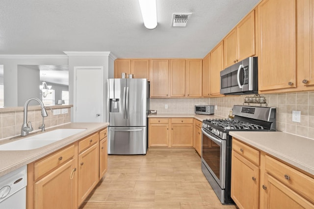 kitchen featuring visible vents, light countertops, stainless steel appliances, light brown cabinetry, and a sink