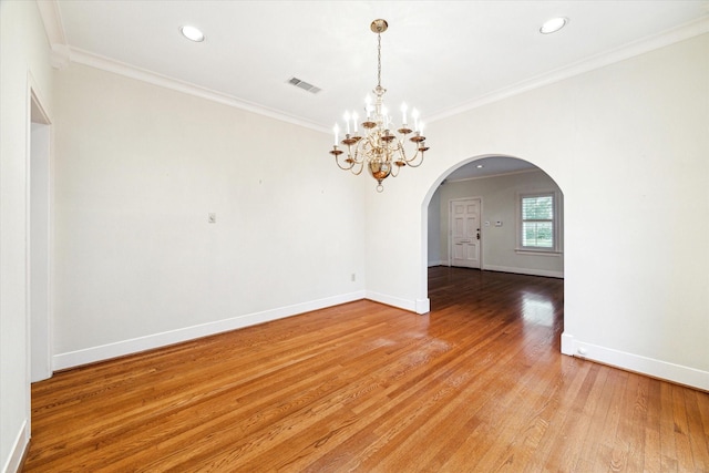 empty room featuring arched walkways, light wood finished floors, visible vents, ornamental molding, and baseboards