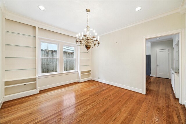 unfurnished dining area featuring a chandelier, light wood-style flooring, recessed lighting, baseboards, and ornamental molding