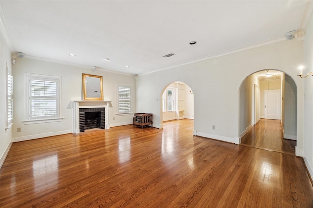 unfurnished living room featuring a brick fireplace, plenty of natural light, baseboards, and wood finished floors