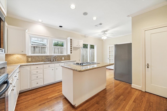 kitchen with visible vents, light wood-style flooring, a kitchen island, freestanding refrigerator, and white cooktop