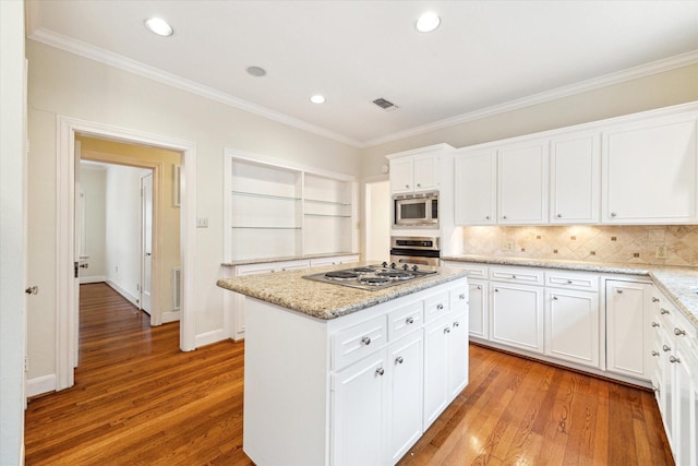 kitchen with a center island, crown molding, appliances with stainless steel finishes, white cabinetry, and light wood-type flooring