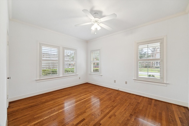 empty room with baseboards, wood finished floors, and crown molding