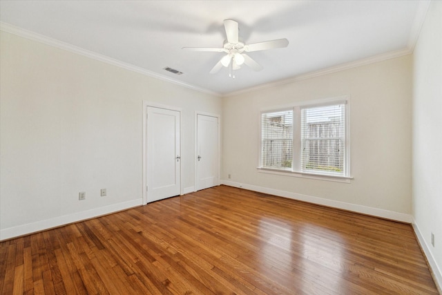 spare room featuring visible vents, baseboards, wood finished floors, and ornamental molding