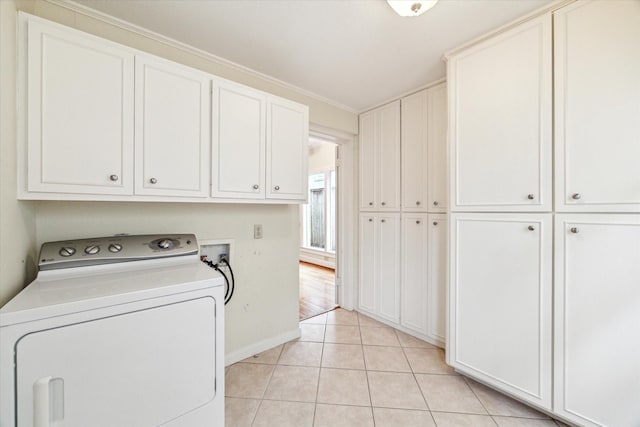 washroom featuring washer / clothes dryer, light tile patterned flooring, cabinet space, and baseboards