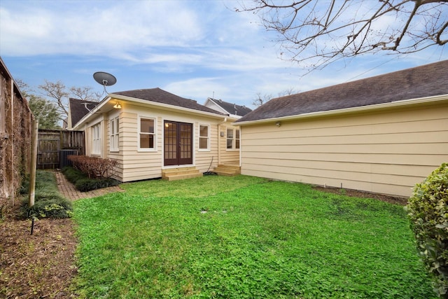 rear view of property featuring entry steps, a yard, and fence