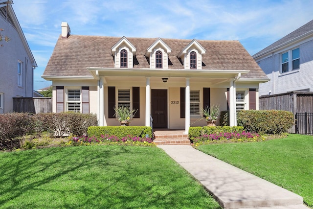 cape cod-style house featuring a porch, roof with shingles, a front yard, and fence