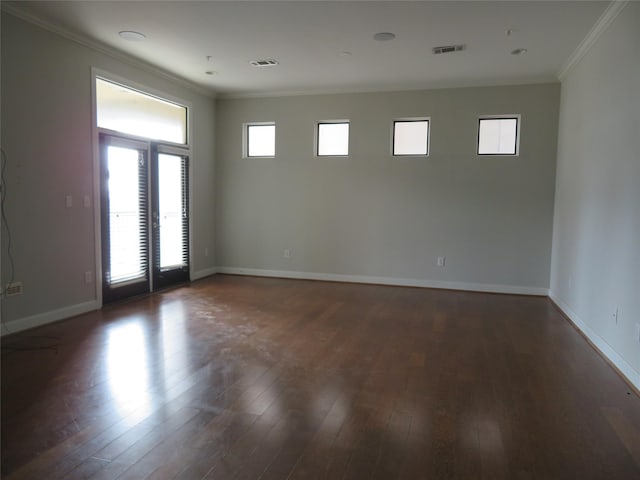 spare room featuring baseboards, visible vents, dark wood finished floors, and crown molding