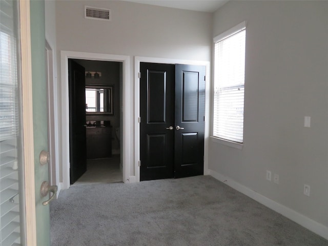 unfurnished bedroom featuring visible vents, baseboards, carpet flooring, a closet, and ensuite bath