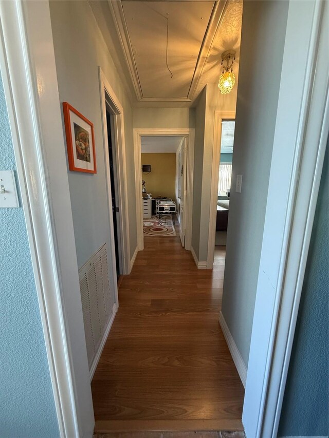 hallway featuring visible vents, dark wood-style flooring, attic access, and baseboards