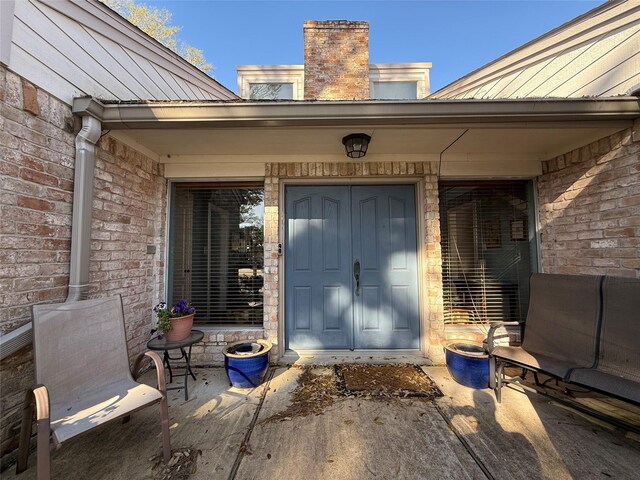 view of exterior entry with brick siding and metal roof