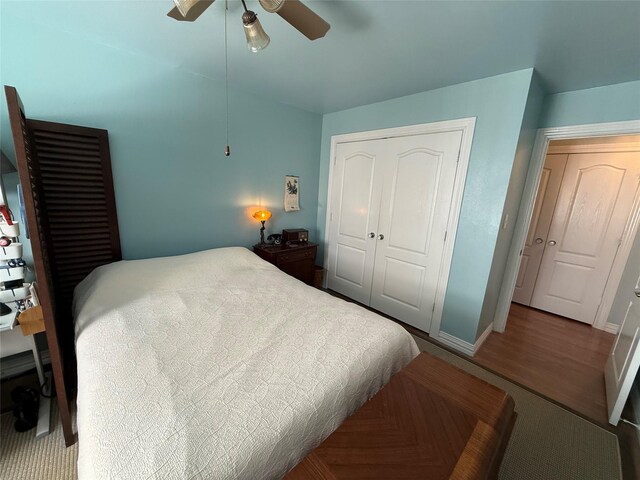 bedroom with ceiling fan, a closet, wood finished floors, and baseboards