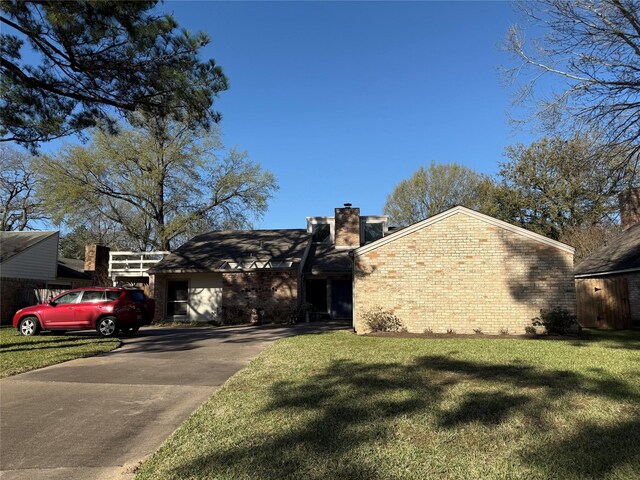 view of front of property featuring driveway, a chimney, a front lawn, and brick siding