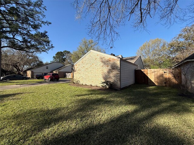 view of home's exterior with brick siding, a yard, and fence