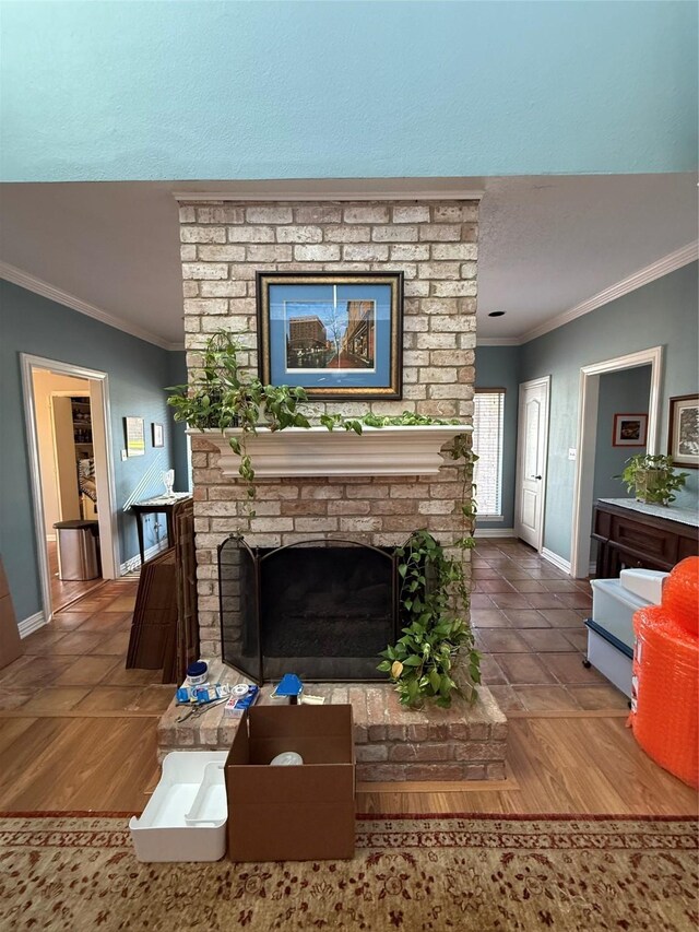 living room featuring a brick fireplace, crown molding, baseboards, and wood finished floors