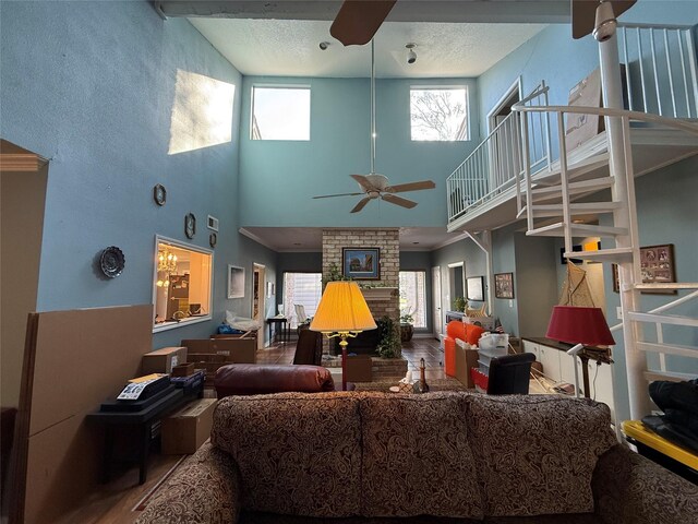 living area with a textured ceiling, a fireplace, a ceiling fan, and wood finished floors