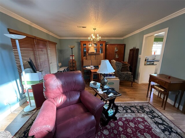 living room with a notable chandelier, crown molding, visible vents, and wood finished floors