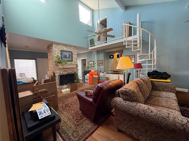 living area with wood finished floors, stairs, a brick fireplace, a wealth of natural light, and crown molding