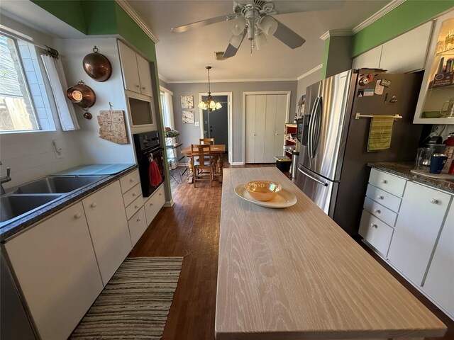 kitchen with oven, dark wood-style flooring, white cabinetry, stainless steel refrigerator with ice dispenser, and crown molding