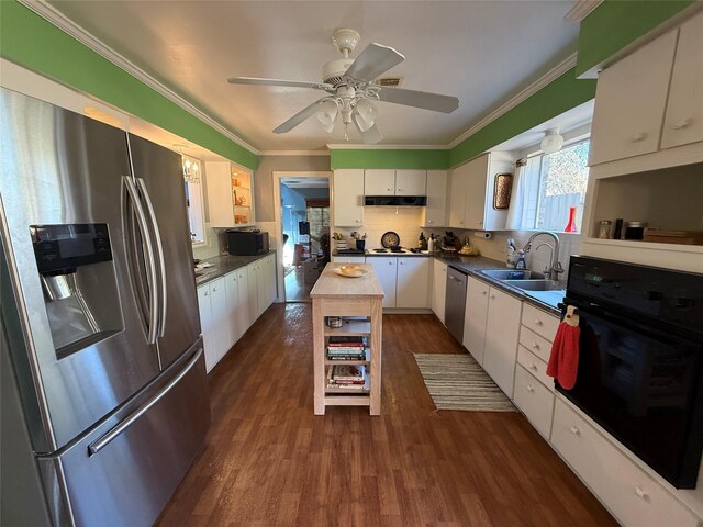 kitchen featuring dark wood-style floors, appliances with stainless steel finishes, ornamental molding, a sink, and under cabinet range hood