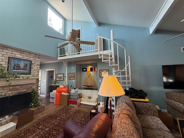 living room with a ceiling fan, stairs, a fireplace, high vaulted ceiling, and beam ceiling