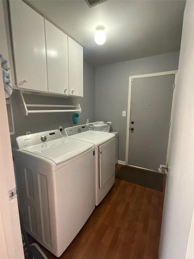 clothes washing area featuring cabinet space, dark wood-style flooring, and washing machine and clothes dryer