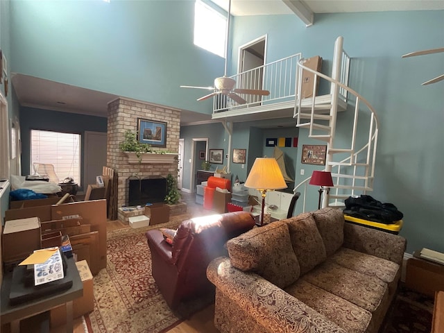 living area featuring high vaulted ceiling, a fireplace, a ceiling fan, stairway, and beamed ceiling