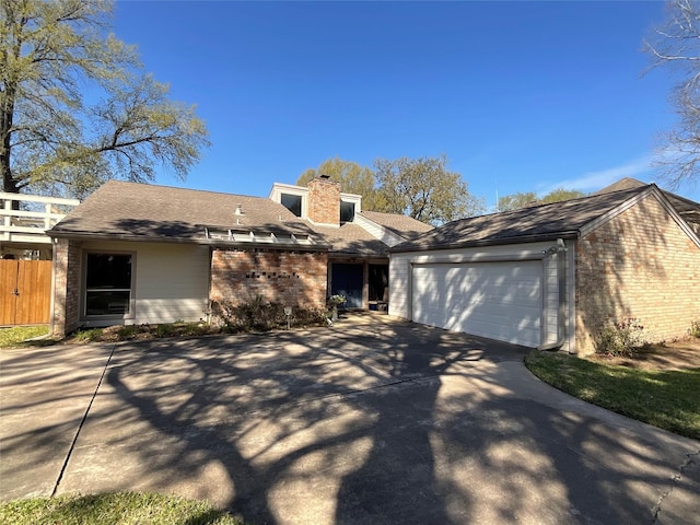 view of front of house featuring a garage, brick siding, fence, concrete driveway, and a chimney