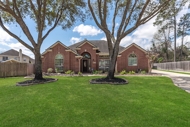 traditional home with brick siding, a front lawn, and fence