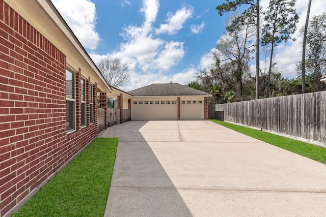 exterior space with brick siding, driveway, and fence