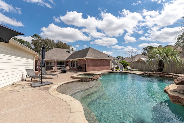 view of swimming pool featuring a pool with connected hot tub, a water slide, a patio, and fence