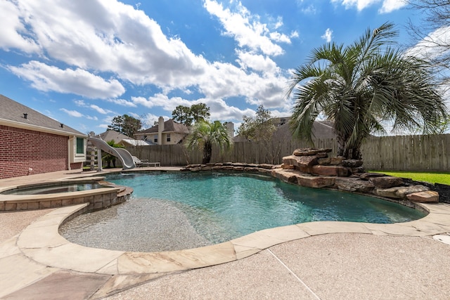 view of swimming pool featuring a patio, a pool with connected hot tub, a water slide, and a fenced backyard