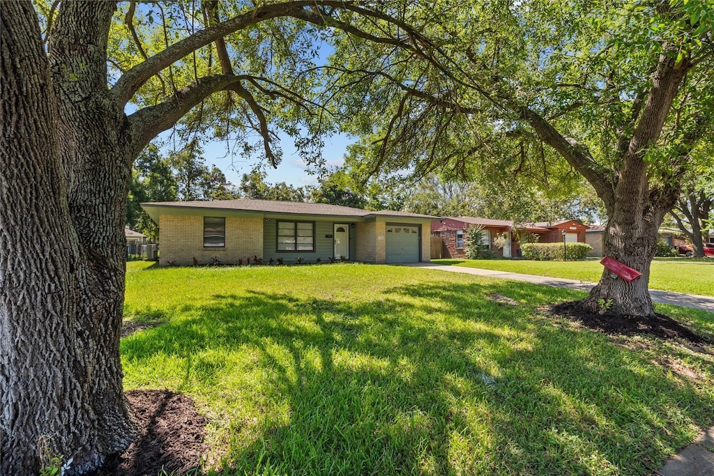 ranch-style home featuring a garage, driveway, a front lawn, and brick siding