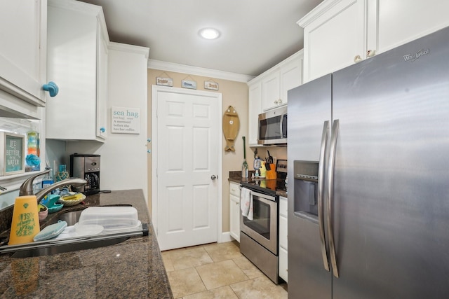 kitchen with stainless steel appliances, a sink, white cabinetry, ornamental molding, and dark stone counters