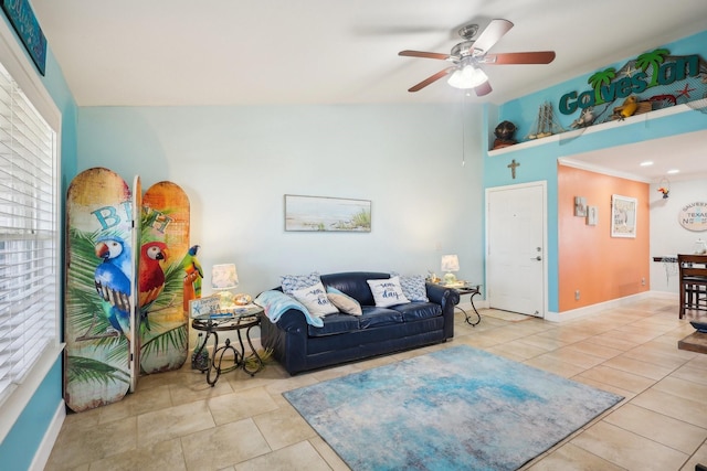 living area with baseboards, a ceiling fan, and tile patterned floors