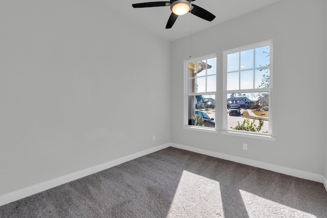 spare room with baseboards, dark carpet, and a ceiling fan