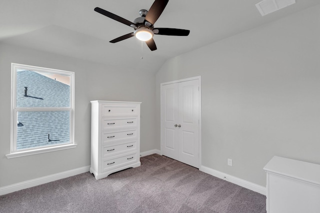 unfurnished bedroom featuring light carpet, a ceiling fan, visible vents, vaulted ceiling, and baseboards
