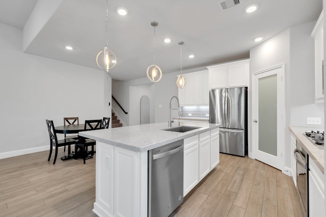 kitchen with stainless steel appliances, visible vents, a kitchen island with sink, a sink, and light wood-type flooring