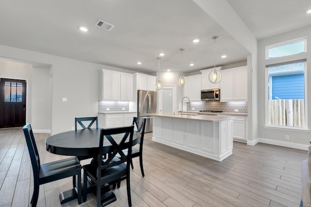 dining space with a wealth of natural light, light wood-type flooring, and visible vents