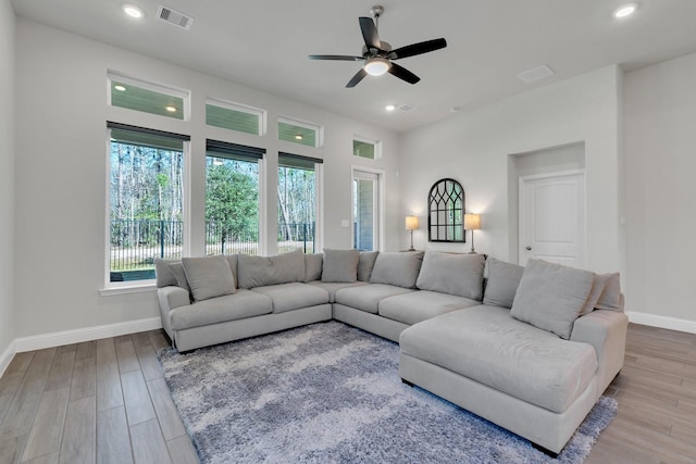 living room with recessed lighting, visible vents, baseboards, and wood finished floors