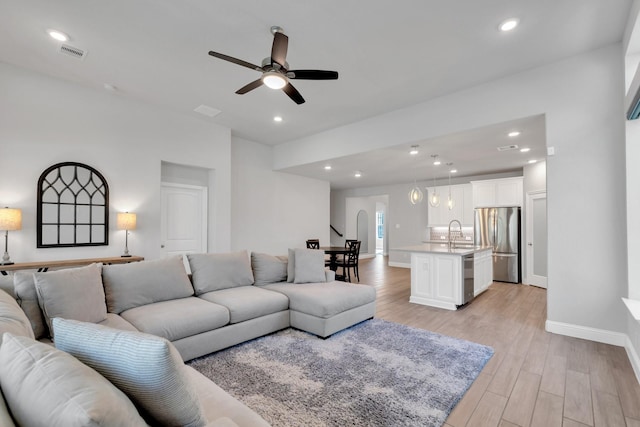 living room with baseboards, visible vents, ceiling fan, light wood-type flooring, and recessed lighting